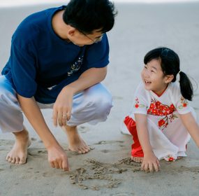 Father and daughter bonding while playing on the sandy beach, sharing joyful moments.